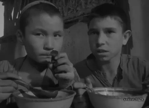 Yan yana oturan iki çocuk, önlerindeki kâselerden yemek yiyor. Sen Yetim Emassan (1962).